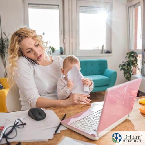 woman looking stressed, carrying baby, and working from home