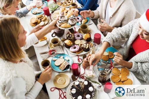 An image of people eating at a long table covered in sweets and unhealthy foods