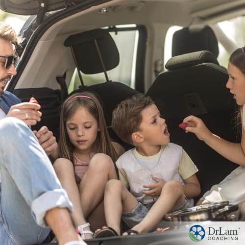 A young family enjoys travel snacks on the side of the road