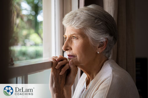 An image of an older woman looking stressed staring out a window