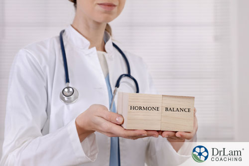 An image of a female doctor holding wooden blocks with hormone balance written on them