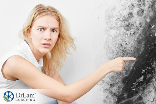 An image of a mother pointing at black mold on her wall looking very worried