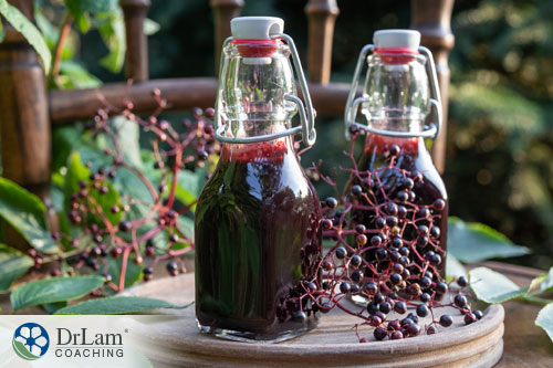 An image of two bottles of elderberry syrup and some elderberries