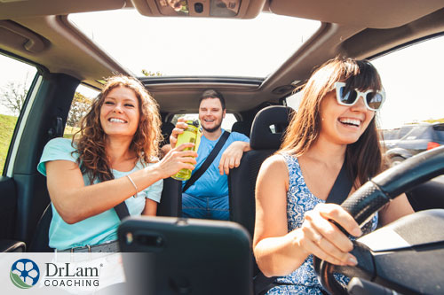 An image of a group of smiling people in a car, sharing a beverage
