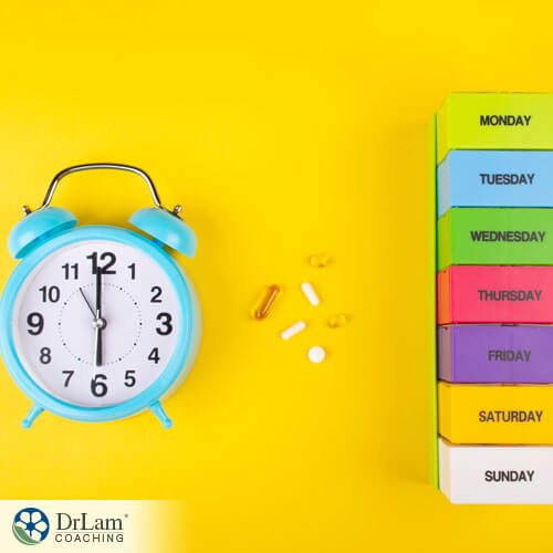 An image of an alarm clock, supplements, and a weekly pill planner