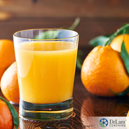 An image of a glass of orange juice with oranges around it