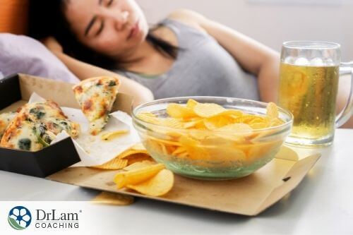 An image of a bowl of nachos, a glass of beer, and a women sleeping in the background