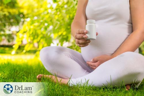 pregnant woman holding bottle of fertility supplements