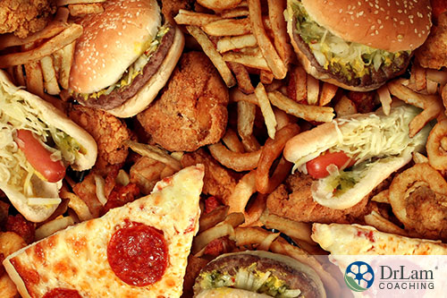 An image of unhealthy foods like hamburgers, pizza and french-fries piled together