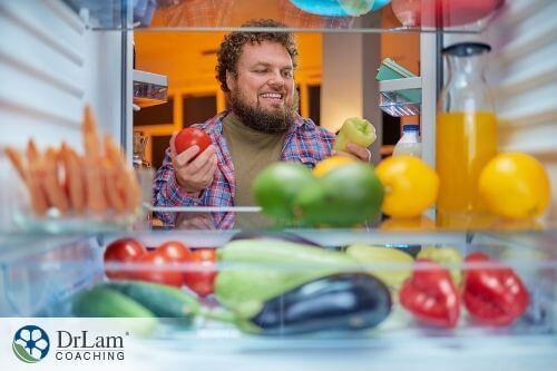 An image of a man in the refrigerator choosing some vegetables