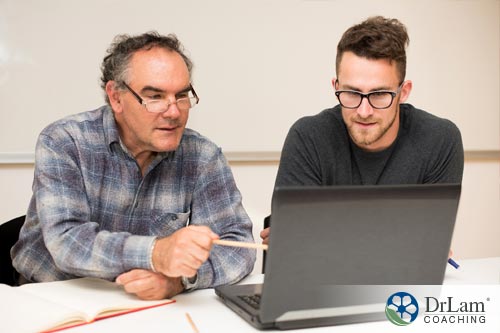 An image of an older man learning more about adrenal exhaustion symptoms on a laptop with help from younger man