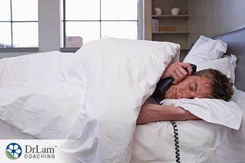 An image of a man laying in bed while holding the phone to his ear
