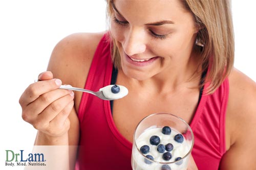 Woman eating yogurt and with blueberries, Learn the link between probiotics and high blood pressure