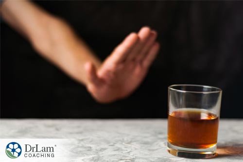 An image of someone signaling no to alcohol and caffeine with a raised hand to the glass