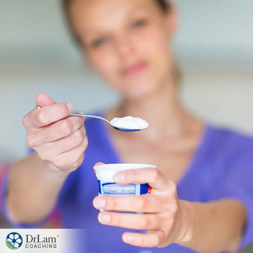An image of a woman holding a yogurt cup and spoon