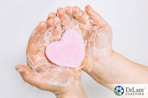 An image of a child's soapy hands holding a heart shaped soap