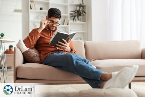 An image of a man with glasses reading a book