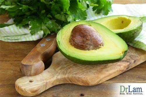 An avocado sliced in half with the pit remining in one half. Avocados are one food rich in the benefits of lysine and other nutrients