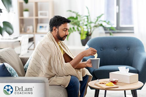 An image of a man drinking tea wearing a blanket