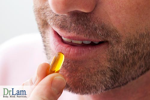 Closeup of a man holding a supplement pill, about to take it, representing the benefits of lysine supplementation