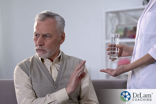 An image of an older man refusing to take a pill