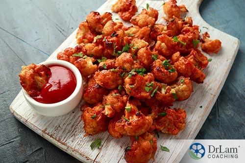 An image of buffalo cauliflower bites on a cutting board with dipping sauce