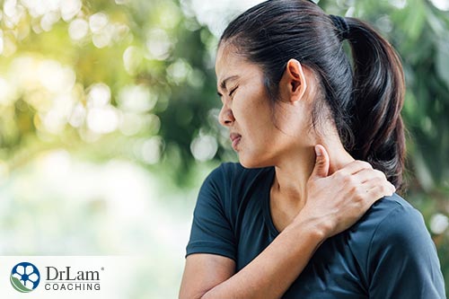 A woman holding her shoulder or lower neck in pain