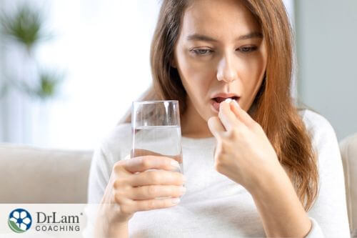 An image of a woman taking a pill with a glass of water