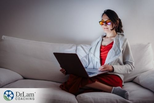 An image of a woman with glasses looking at her laptop