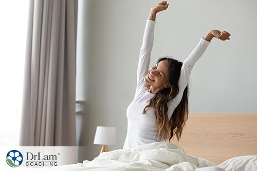 An image of a woman in bed waking up and smiling