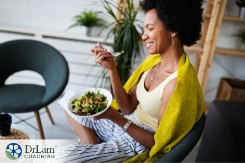 An image of a woman on a chair eating a vegetable salad