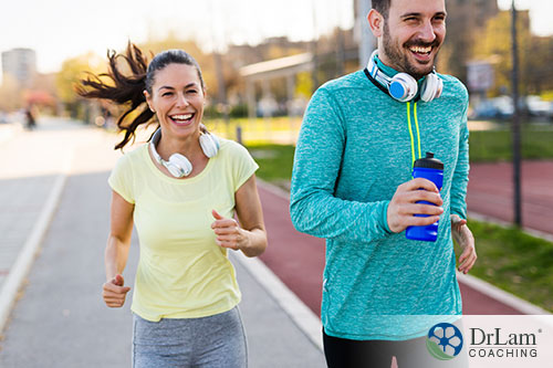 An image of a man and woman jogging with headphones around their necks
