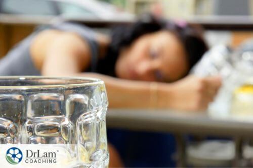 An image of a woman passed out on the table showing an empty glass of alcohol