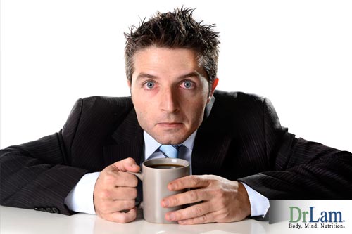 A frazzled looking man clutching a coffee cup, who would benefit from diet changes to soothe hypoglycemia symptoms.