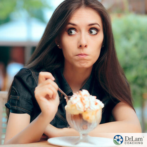 An image of a young lady with a guilty look on her face while eating a sweet treat