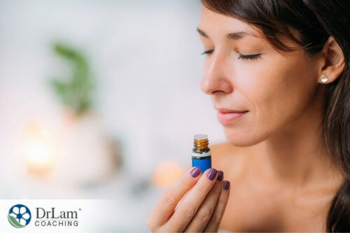An image of a woman smelling a bottle of essential oil