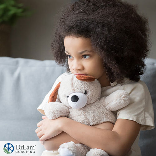 An image of a sad little girl holing her stuffed animal