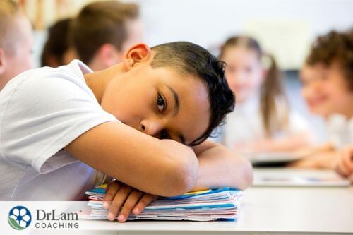 An image of a young boy with his head on the desk