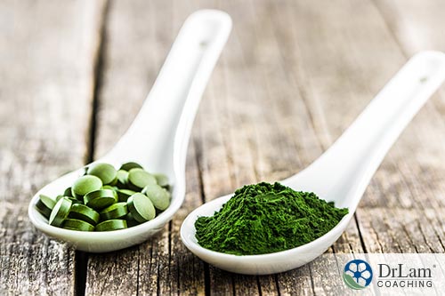 An image of two soup spoons containing chlorella one in tablets and one in powder