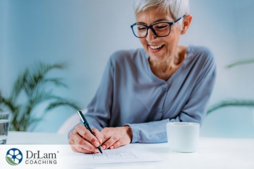 An image of a senior woman smiling while writing symbolizing healthy brain activity