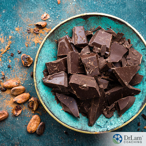 An image of a bowl of dark chocolate with cocoa beans next to it
