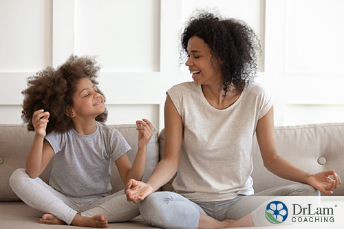An image of a mother and daughter meditating and smiling