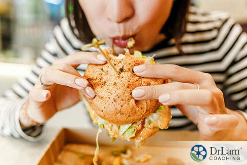 An image of a woman eating a large hamburger