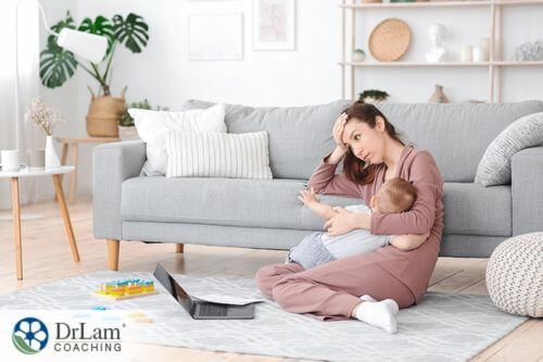 An image of a stressed out mother holding her baby and forhead