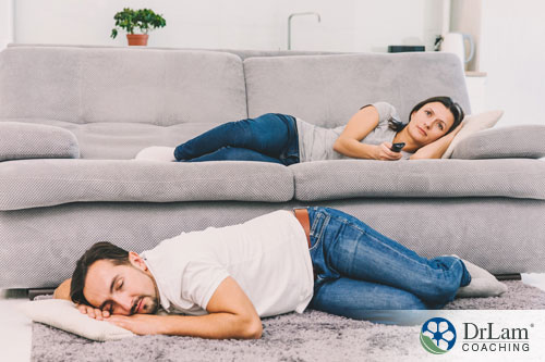 An image of a fatigued couple laying on the couch and floor due to lack of sleep