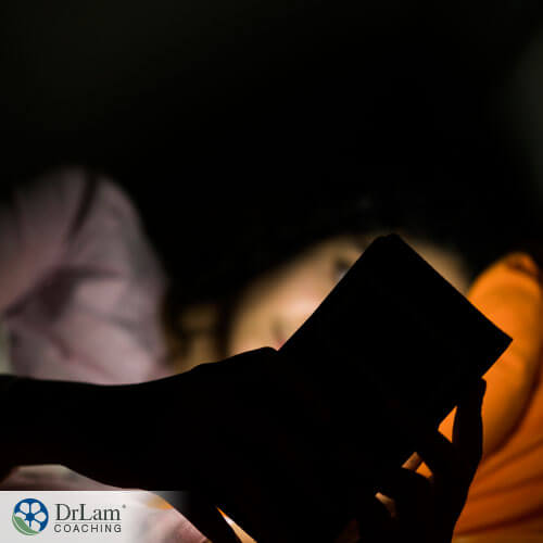 An image of a woman on her phone in the dark while in bed