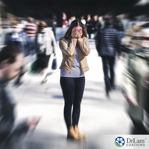 An image of an overwhelmed woman holding her face in a crowded area