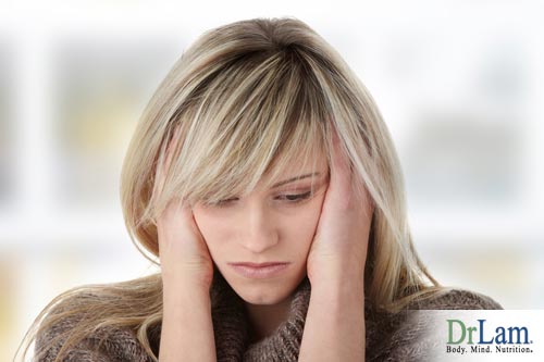 Woman holding the sides of her head and looking depressed. Depression and adrenal fatigue can be deep rooted problems that need a holistic approach.