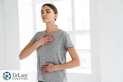 An image of a woman with her hands on her chest and abdomen mindfully breathing