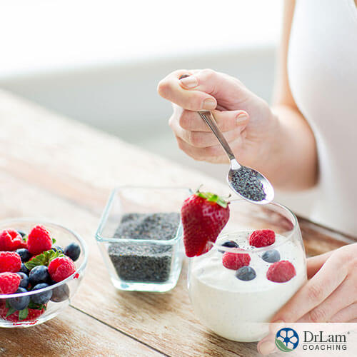 An image of a woman spooning chia seeds into a small glass of yogurt and berries